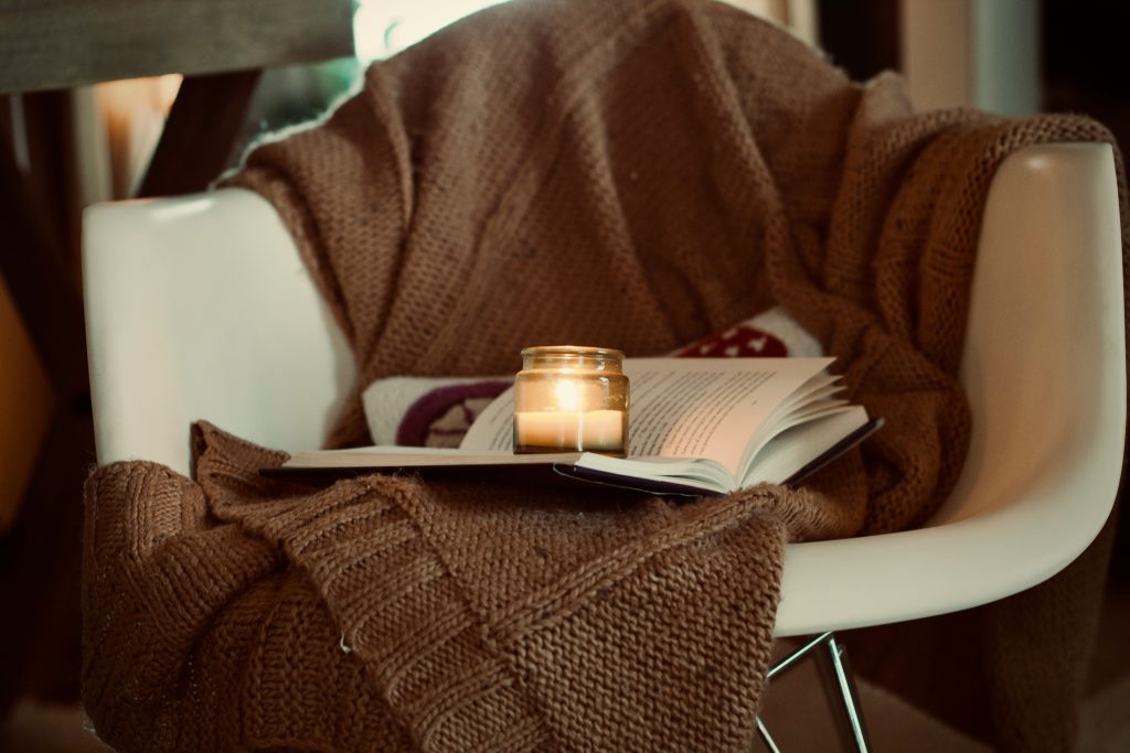 evening routine for remote workers candle and book resting on armchair