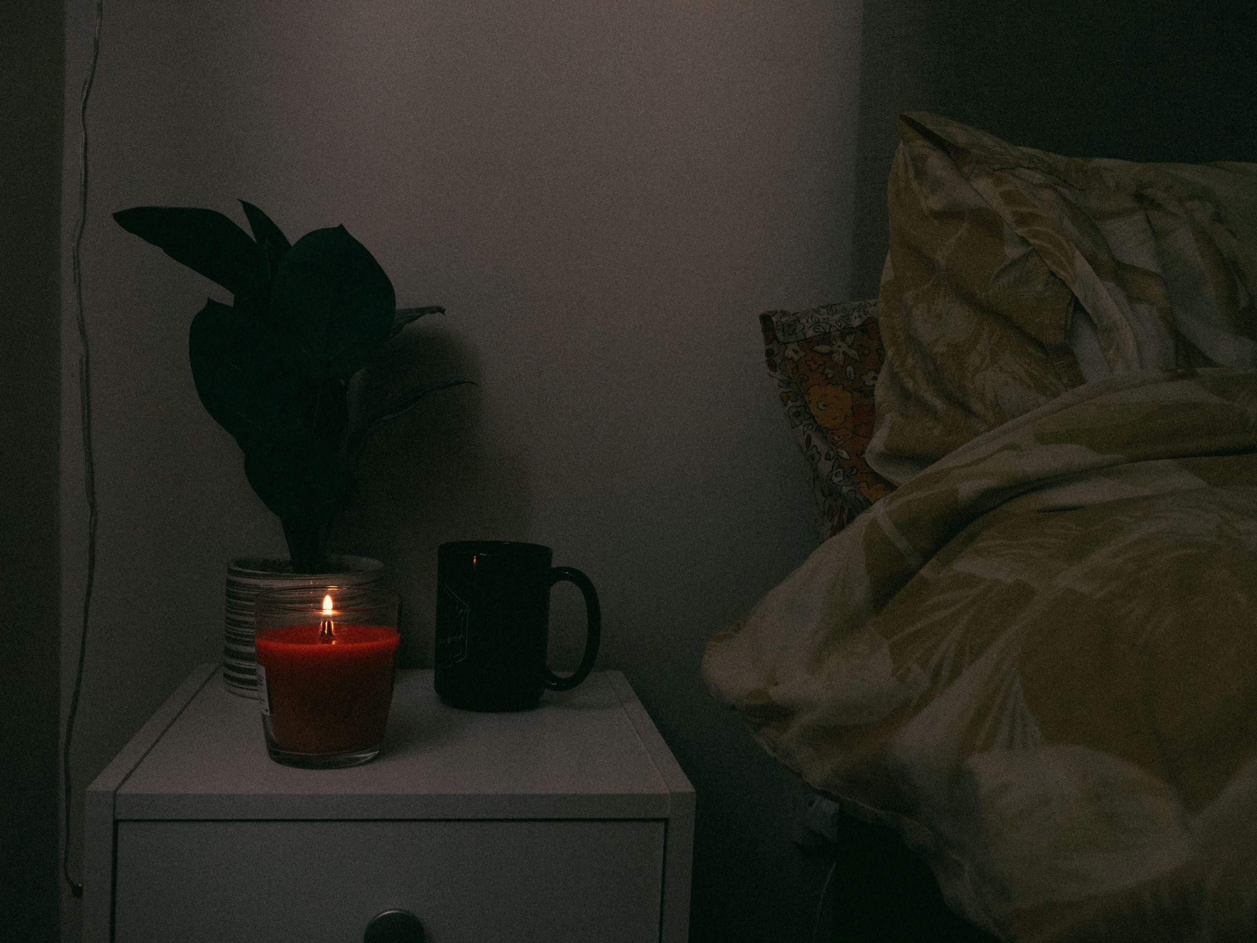 nightstand with candle and plant to support sleep schedule wind-down