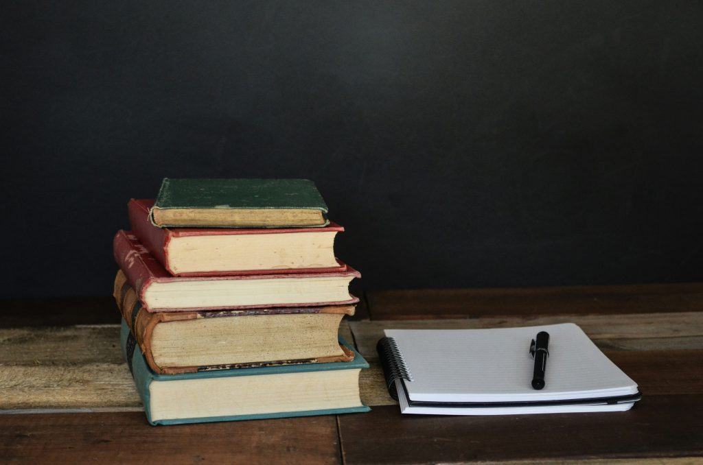 pile of productivity books on desk with pen