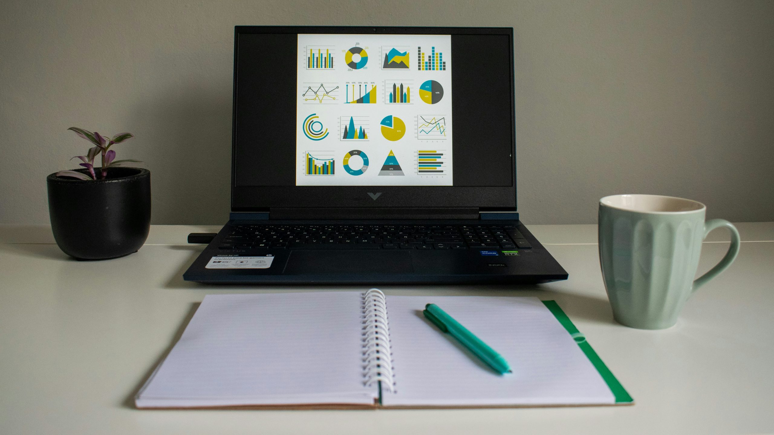 laptop displaying data charts next to a notebook, remote work trends 2026